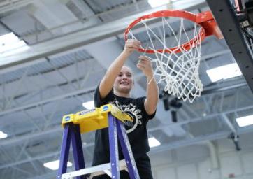Women's basketball player Brianna Bailey cutting down the nets after 密歇根州立大学丹佛's 2022 RMAC championship